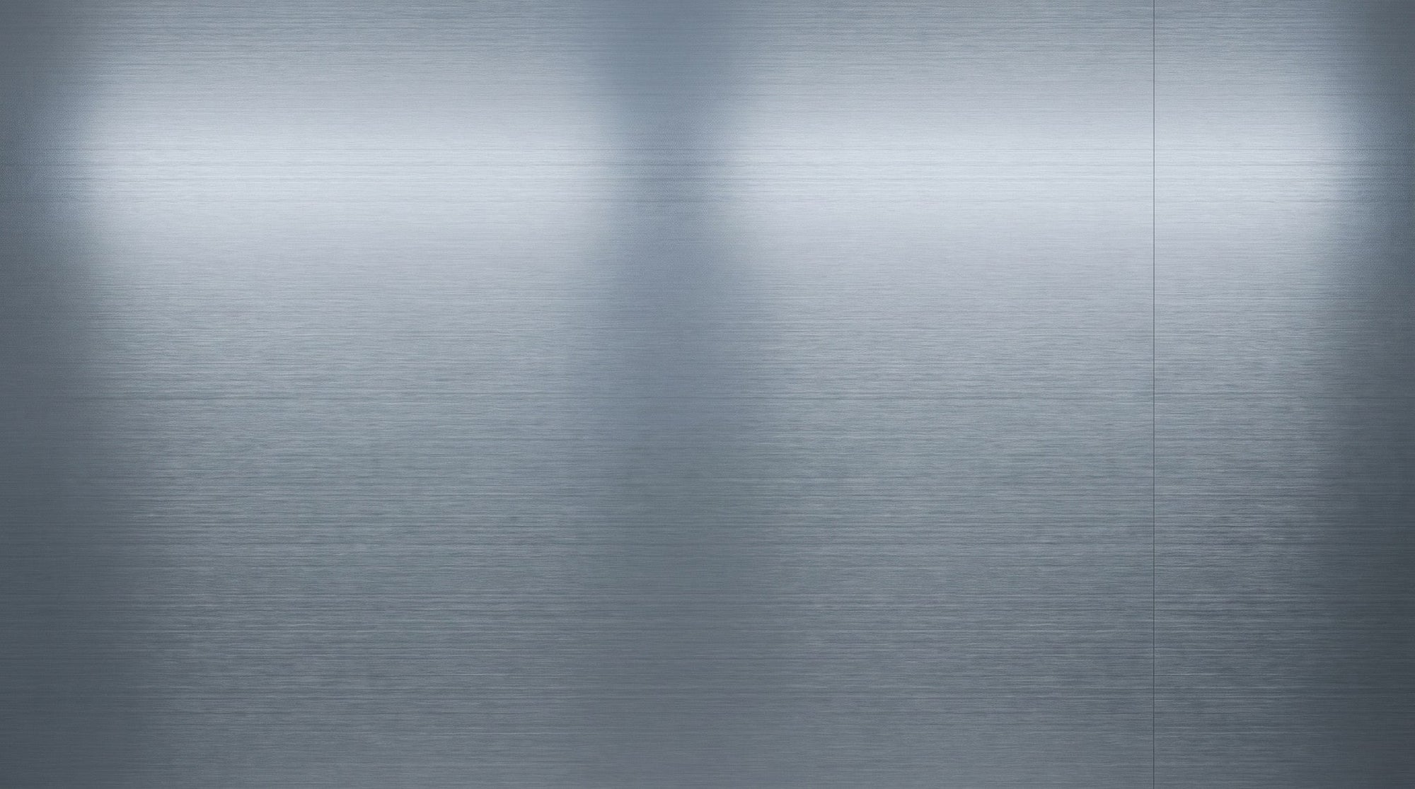The fine horizontal grain of a clean brushed stainless steel surface filling the frame, with a soft reflection across it.